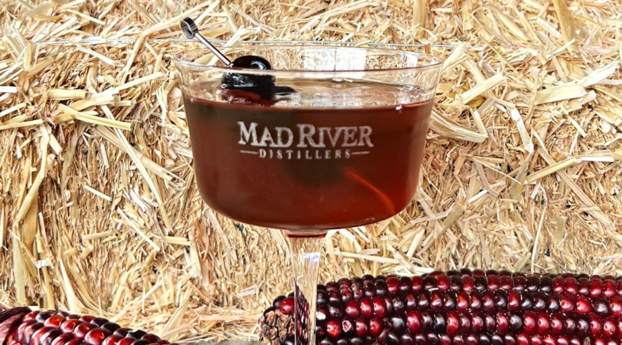 Rye Manhattan on a table in front of straw and corn