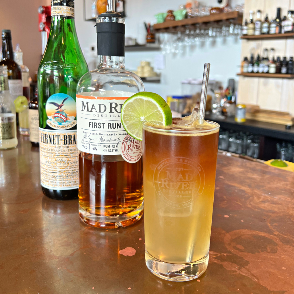 A Midday Reviver cocktail on the Mad River Distillers bar with a bottle of First Run Rum and Fernet in the background