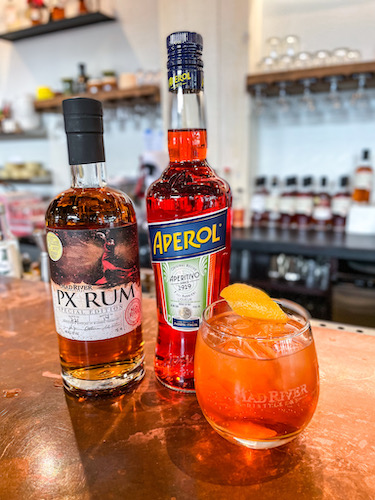 Bottle of PX Rum, Aperol and a cocktail on a bar