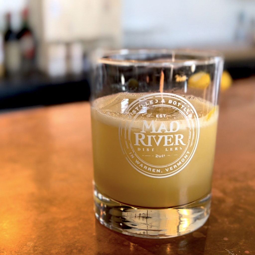 Glass filled with Rye Gold Rush cocktail on a bar counter