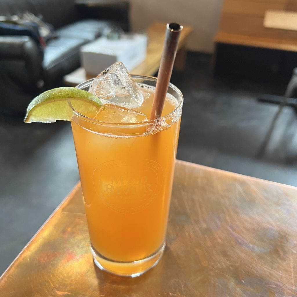 glass of Rum Punch with straw and lime wedge on bar counter