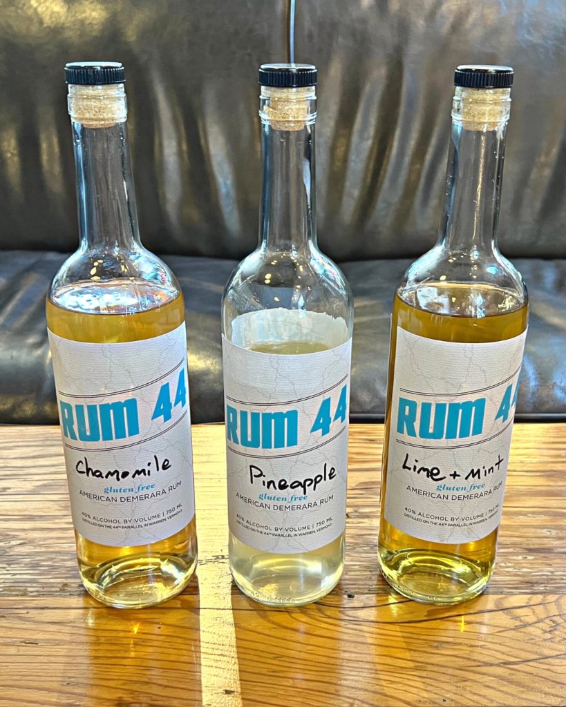 Three bottles of Rum 44 on a table, each with the words Chamomile, Pineapple, and Lime & Mint,