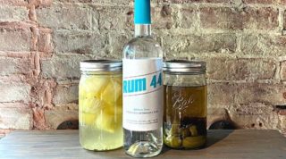 A bottle of Rum 44 is between two bottles of rum infusions in mason jars