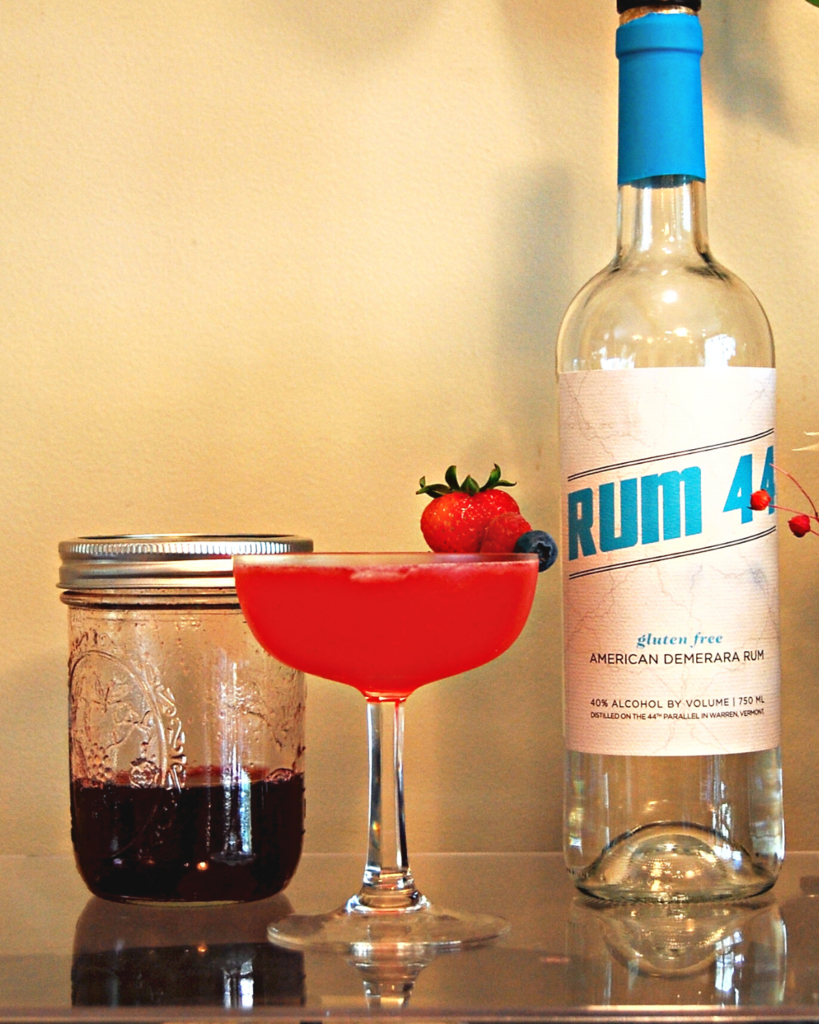 Rumberry Daiquiri next to a jar of berry simple syrup and Rum 44