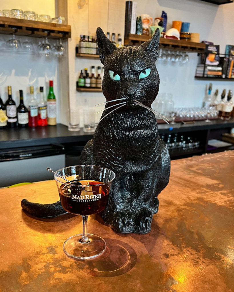 Black Manhattan cocktail with black cat decoration