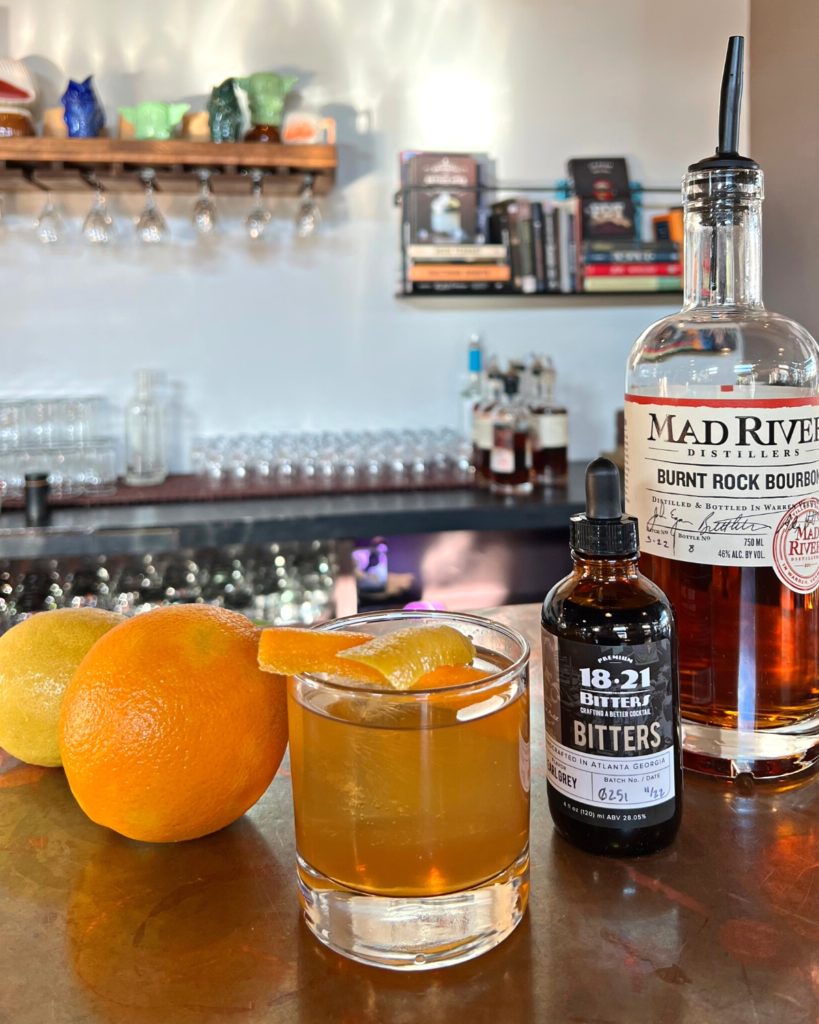 An Earl Grey Tea Old Fashioned on the tasting room bar with a bottle of Burnt Rock Bourbon and 18.21 Bitters