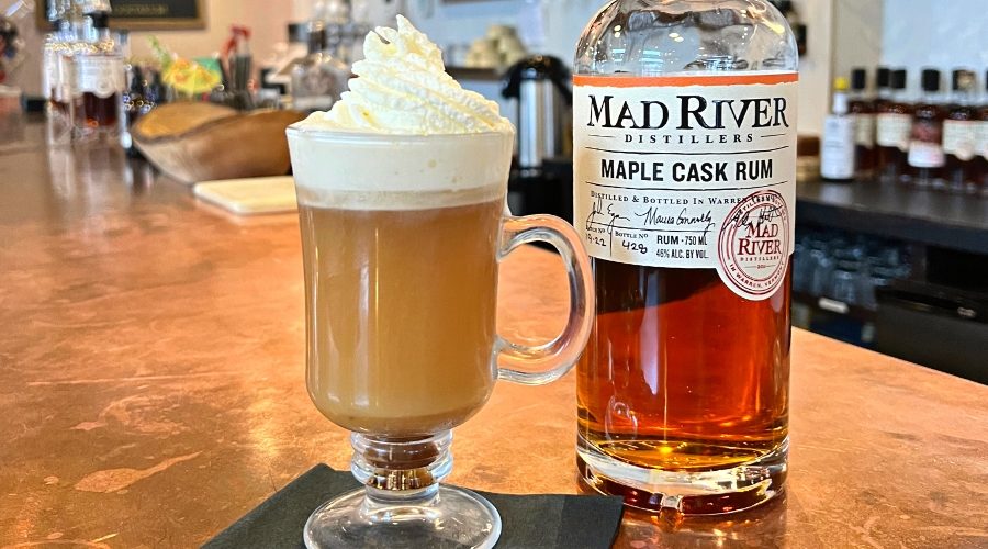 Hot Buttered Rum Cocktail on the Tasting Room bar next to a bottle of Maple Cask Rum