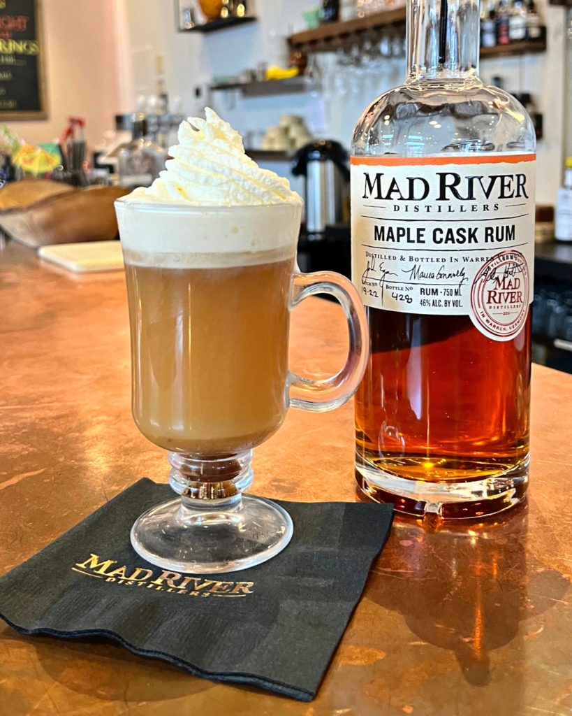 Hot Buttered Rum cocktail next to a bottle of Maple Cask Rum on a bar