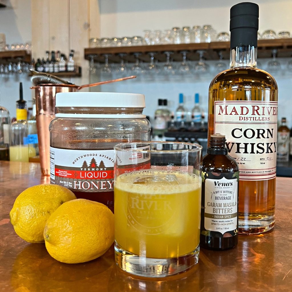 Stolen Gold cocktail with lemons, honey, bitters and a bottle of corn whisky