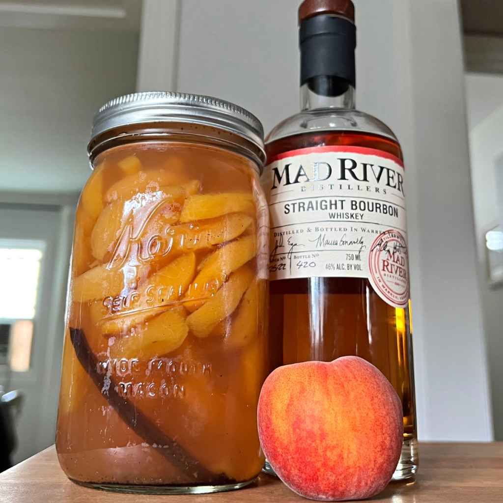 A jar of Straight-Bourbon poached peaches and a bottle of Bourbon on a counter
